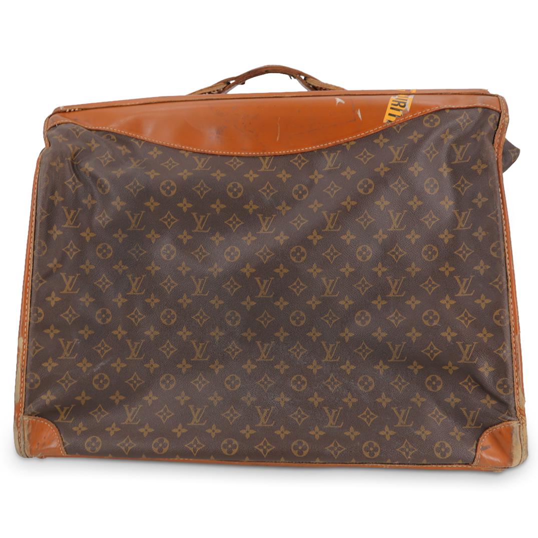 Vintage Louis Vuitton Garment Bag: DESCRIPTION: A vintage Louis Vuitton garment bag luggage, featuring brown printed monogram coated canvas, brass hardware, leather trim, leather trim embellishment, and brown canvas lining. With handle