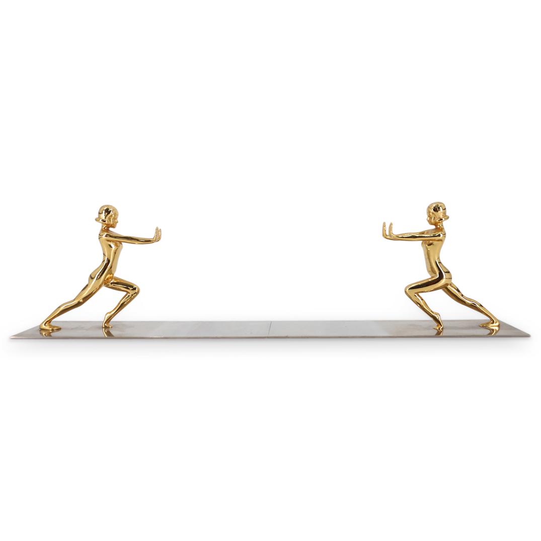 Pair of Mid Century Parcel Gilt Nude Bookends: DESCRIPTION: (2Pc) Pair of mid century bookends featuring parcel gilt sculptural nude women with outstretched pressing arms atop a chrome base. CIRCA: Mid 20th Century ORIGIN: Continental DIMENSIONS: