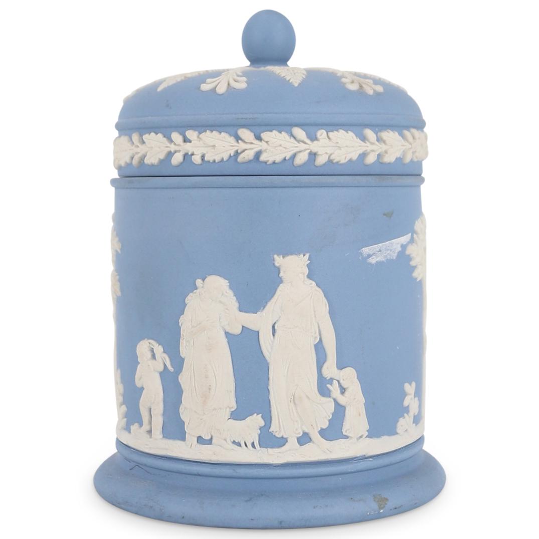 Wedgwood Jasperware Porcelain Tobacco Jar: DESCRIPTION: A Wedgewood Porcelain tobacco box features in a celestial blue ground decorated along the body with Neoclassical figures and leaf motifs, stamped along the underside "Wedgwood England". C