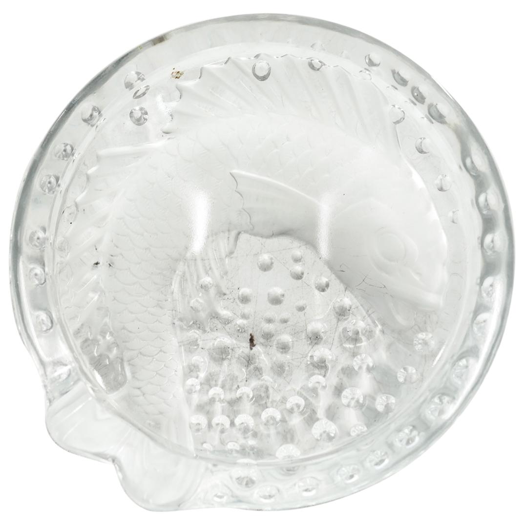 Lalique "Concarneau" Frosted Crystal Ashtray: DESCRIPTION: Lalique frosted crystal ashtray "Concarneau" featuring a depiction of a koi fish with its tail forming a holder at the rim completed by details of scales and fins. Etched signatures at th
