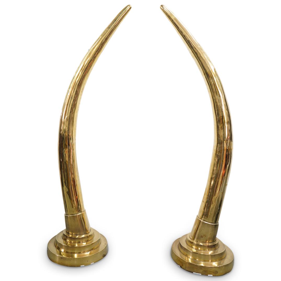 Mid Century Karl Springer Style Large Brass Tusks: DESCRIPTION: Pair of Mid Century Hollywood Regency Karl Springer style large brass tusk sculptures mounted in tiered round bases and presenting a gold tone throughout. CIRCA: Mid 20th Century ORIGIN: