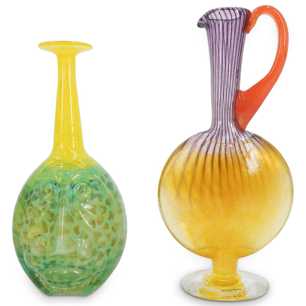 (2Pc) Kosta Boda K. Engman Glass Vase & Decanter: DESCRIPTION: (2Pc) Kjell Engman for Kosta Boda, art glass vase and decanter with stickers at the sides. Includes: (1) "Rio" vase, presenting a face in relief at the green body, transitioning to a brig