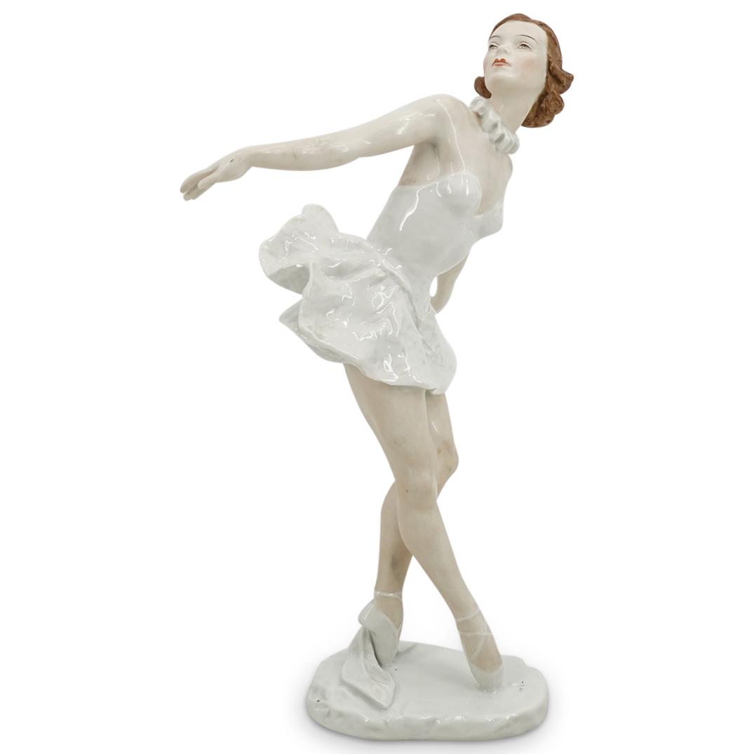 Rosenthal "Marianne Simson" Ballerina Porcelain Sculpture: DESCRIPTION: Lore Friedrich Granau Rosenthal porcelain sculpture titled "Marianne Simson"; depicting a ballerina posing atop her tip toes and wearing white with further red and brown details at the ha