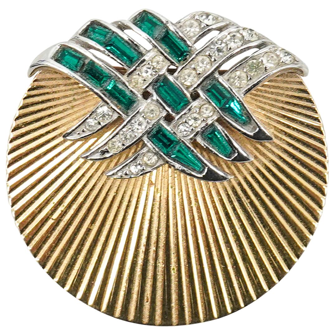 Vintage Marcel Boucher Designer Gilt Brooch: DESCRIPTION: Marcel Boucher gilt designer brooch featuring a textured, gilt disc adorned with ribbons embellished with green and white gemstones. Marked "BOUCHER" on verso. CIRCA: Early 20th Century O