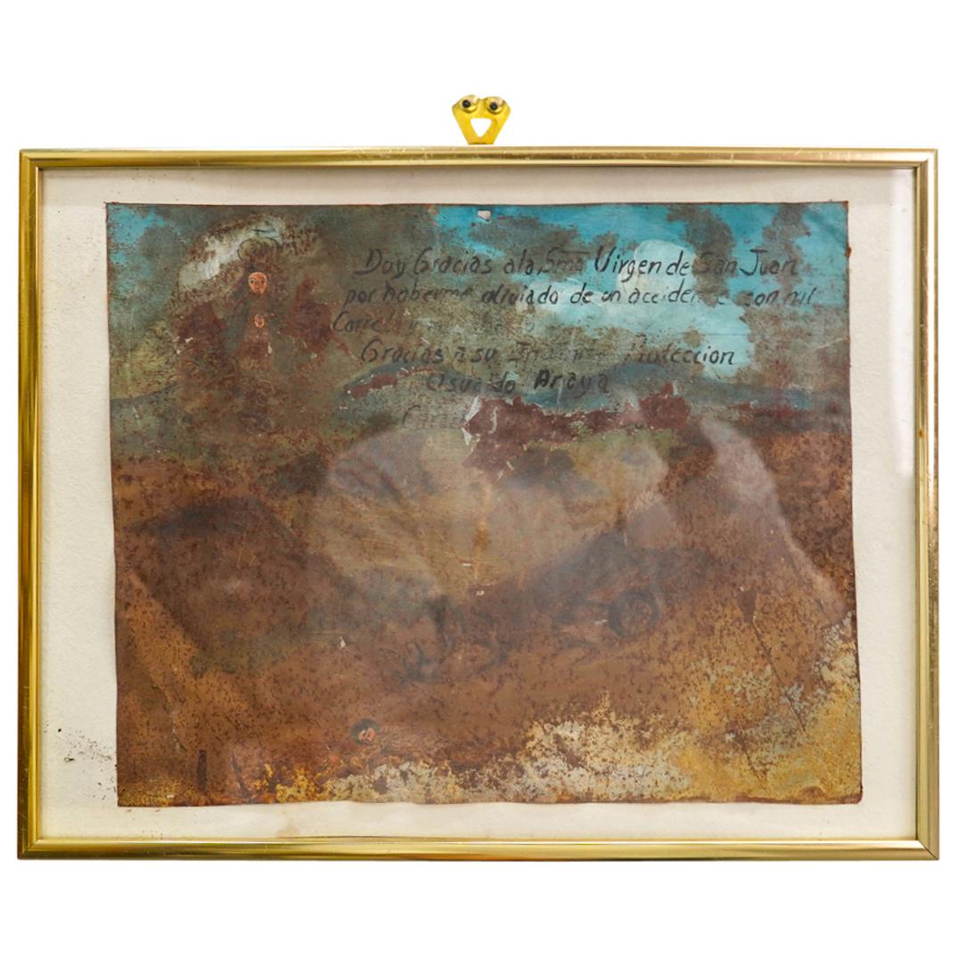 Antique South American Catholic Oil Painting on Tin: DESCRIPTION: Antique South American oil painting on tin, depicting a haloed figure in the clouds above a landscape with a figure, a cart and an ox alongside Spanish script. Mounted in a gold toned met
