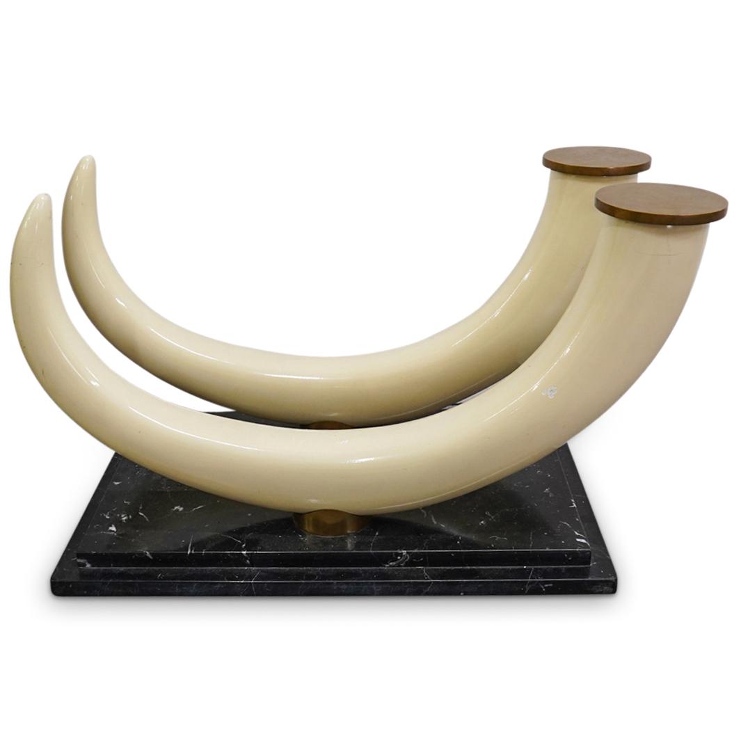 Hollywood Regency Style Tusk And Marble Table: DESCRIPTION: Hollywood Regency table composed of two composite tusk-form supports featuring gilt brass ends and mounted on a white veined, black marble base. CIRCA: 20th Century ORIGIN: Continental DI
