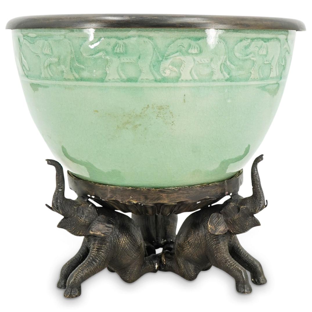 Decorative Celadon Elephant Theme Planter: DESCRIPTION: Decorative crackle glazed celadon planter with elephant decoration, fitted with bronze toned metal trim at lip and raised on a trunk up elephant footed base. Marked: Baan Celadon, Made In
