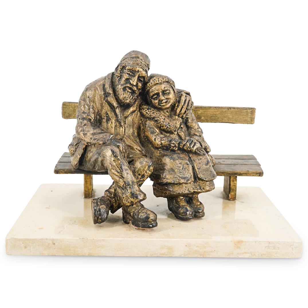 After Nicky Imber "Forever Young" Resin Sculpture: DESCRIPTION: Resin sculpture after artist Nicky Imber's work titled "Forever Young"; Depicting a couple hugging and seated on a bench. Incised signature at the backside "Imber". Mounted on a tan stone