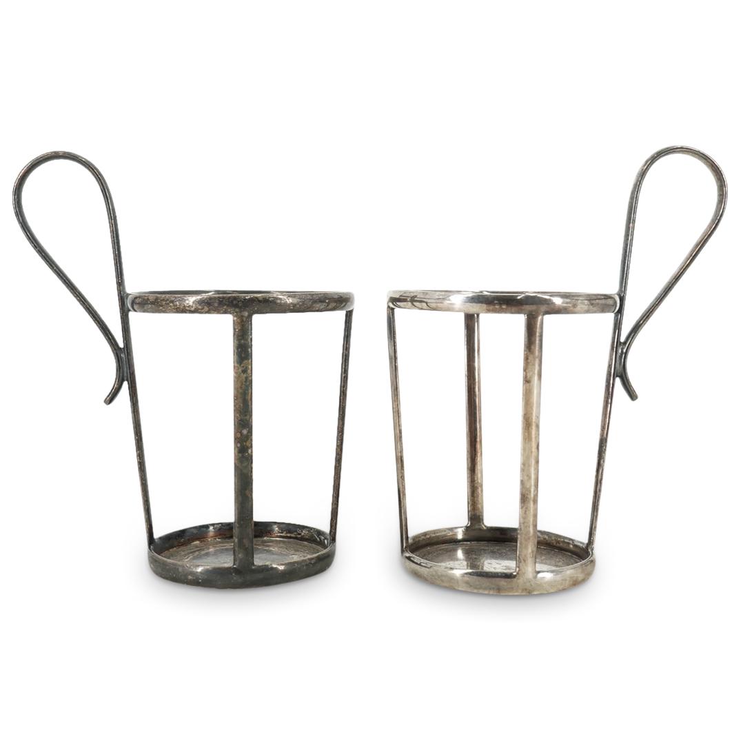 Pair of Antique Thomas Goode & Co Sterling Silver Cup Holders: DESCRIPTION: Pair of Antique Thomas Goode & Co Sterling silver cup holders comprising of frames with four rails, and scroll handles. Impressed at the underside "Thomas Goode & Co South Audley Street 7