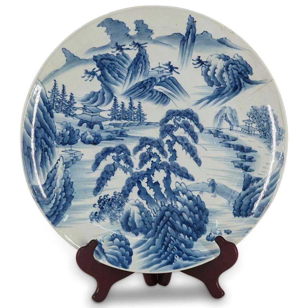 Vintage Chinese Blue And White Porcelain Charger: DESCRIPTION: Blue and white porcelain charger an image of a riverside mountain village populated by a human figure walking across a bridge. Underside bears a deposit ticket for Benjamin R. Wyatt Jr. C