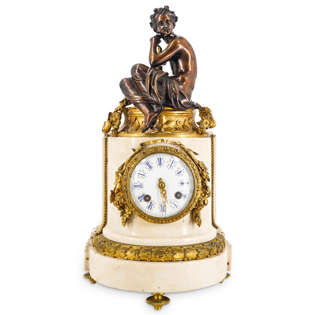 Antique French Marble & Gilt Bronze Taveau Freres Clock: DESCRIPTION: Taveau Freres tripod clock featuring a marble housing crowned with a bronze nude woman wearing a rose crown, covering her legs with a skirt, and flanked by gilt bronze garland. Clock dial