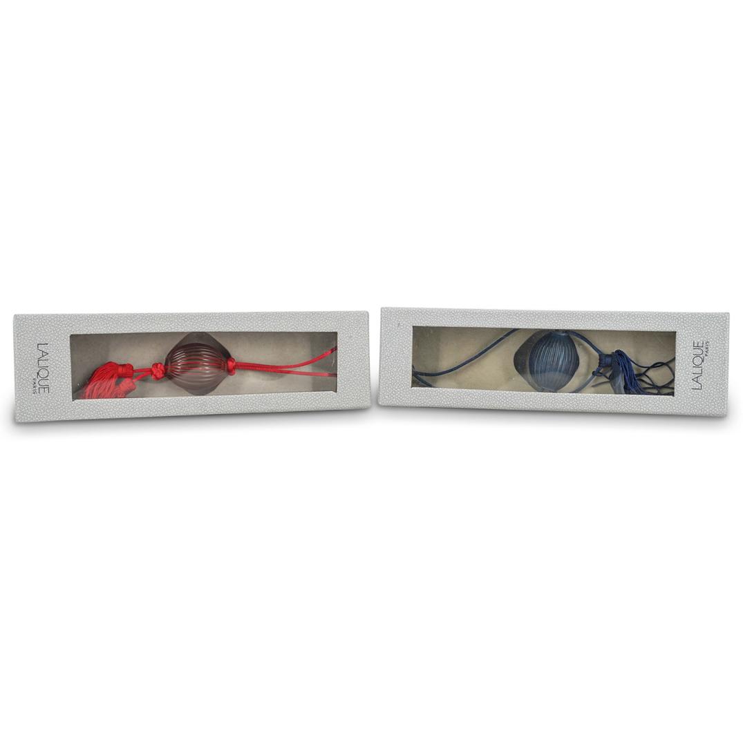 (2 Pc) Pair Of Lalique Crystal Tassels: DESCRIPTION: (2 Pc) A Pair of Lalique crystal tassels in red and navy blue colors. With original "Lalique" packaging box. CIRCA: 20th Century. ORIGIN: France. DIMENSIONS: L: 8" Have a similar item to 