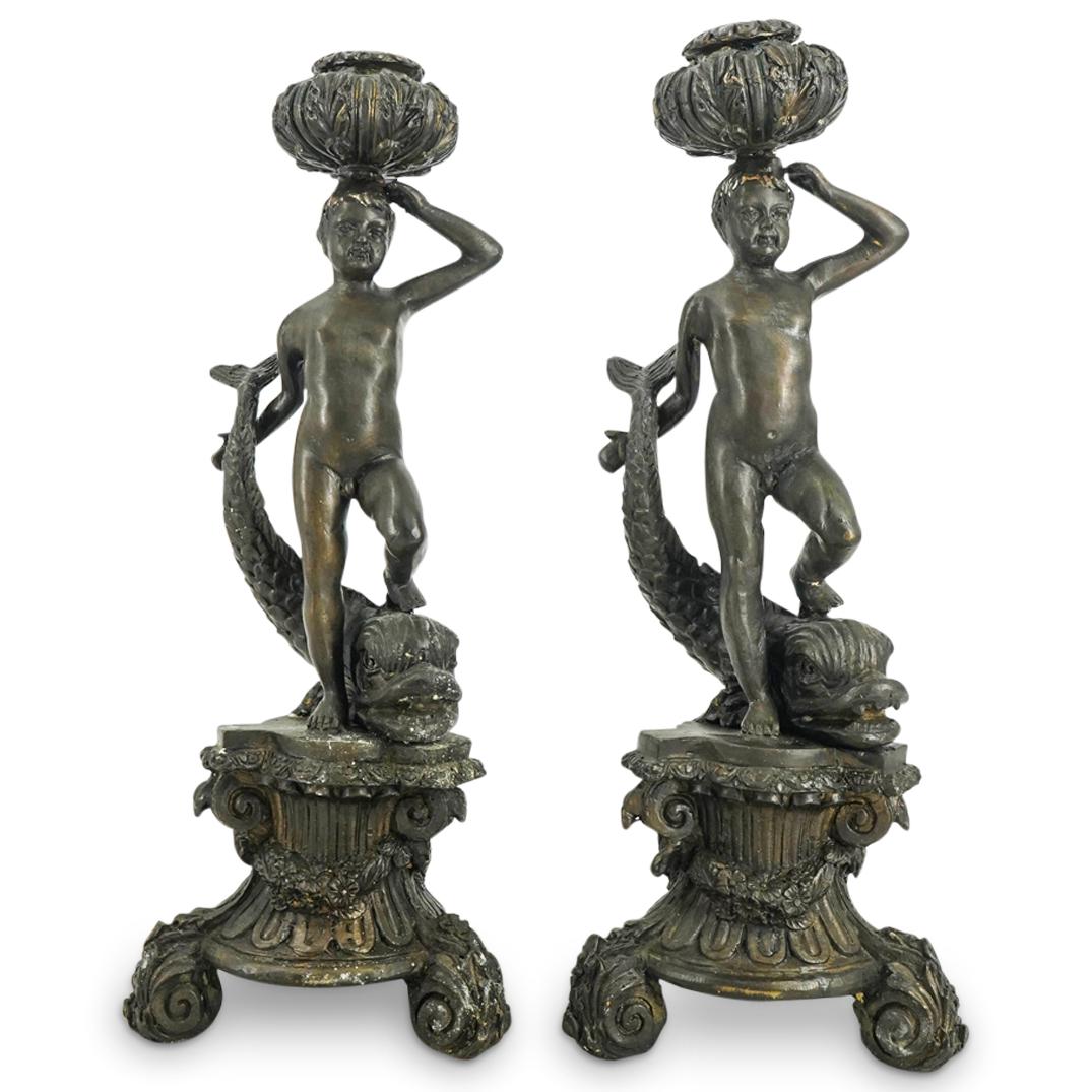 Pair of Mixed Metal Figural Candlesticks: DESCRIPTION: (2 Pc) Matching pair of figural candlesticks depicting a nude boy figure, in a standing pose with his left foot atop a dolphin while holding the dolphin tail with his right arm. The boy f