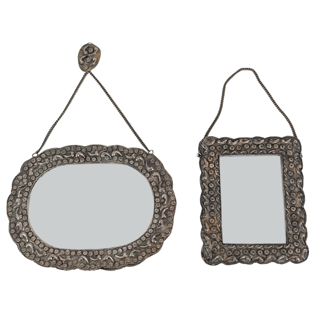 Pair Of Southeast Asian Silver Framed Mirrors: DESCRIPTION: Two mirrors mounted in 800 silver frames decorated with flowers, comma shaped designs, and filigree trimmings. Each piece has a hanging chain and an insert on verso: turquoise for round m