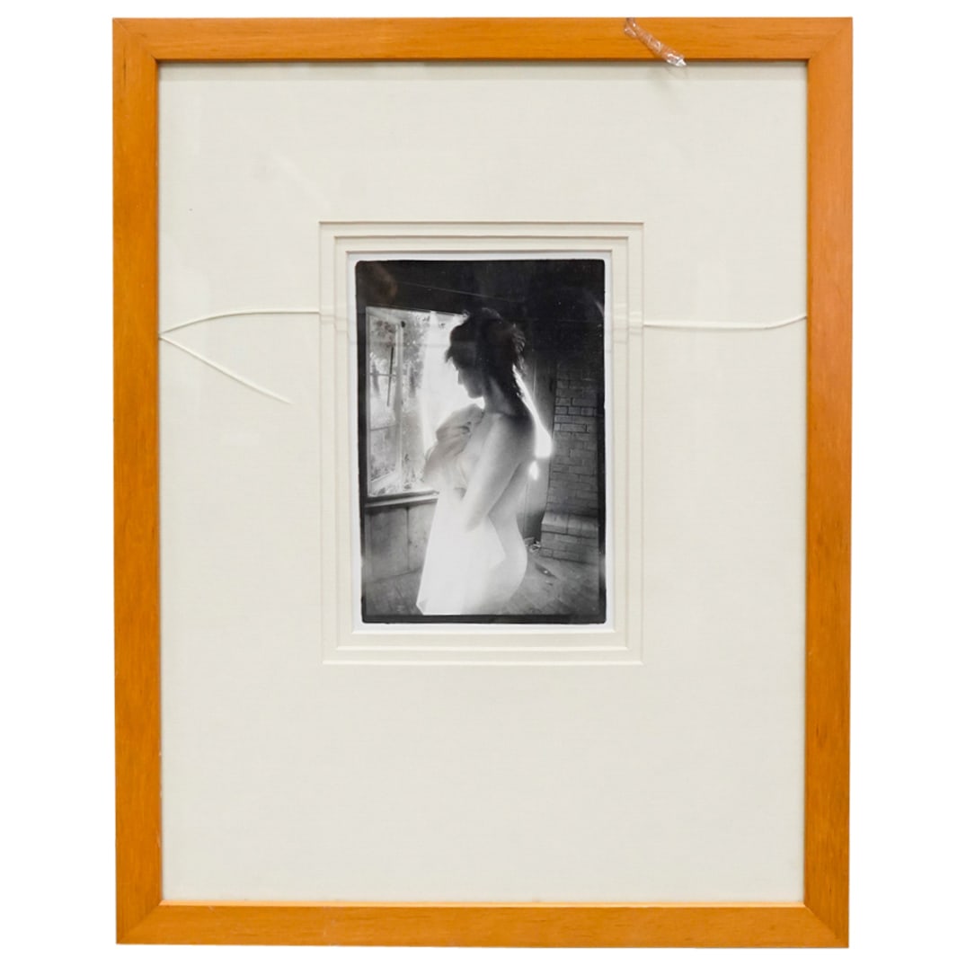 Erotic Nude Woman W/ Sheet Photograph: DESCRIPTION: Erotic monochrome photograph depicting a nude woman holding a transparent sheet to her breast before an open window casts light upon her skin. Mounted in a wooden frame. CIRCA: 20th Centu