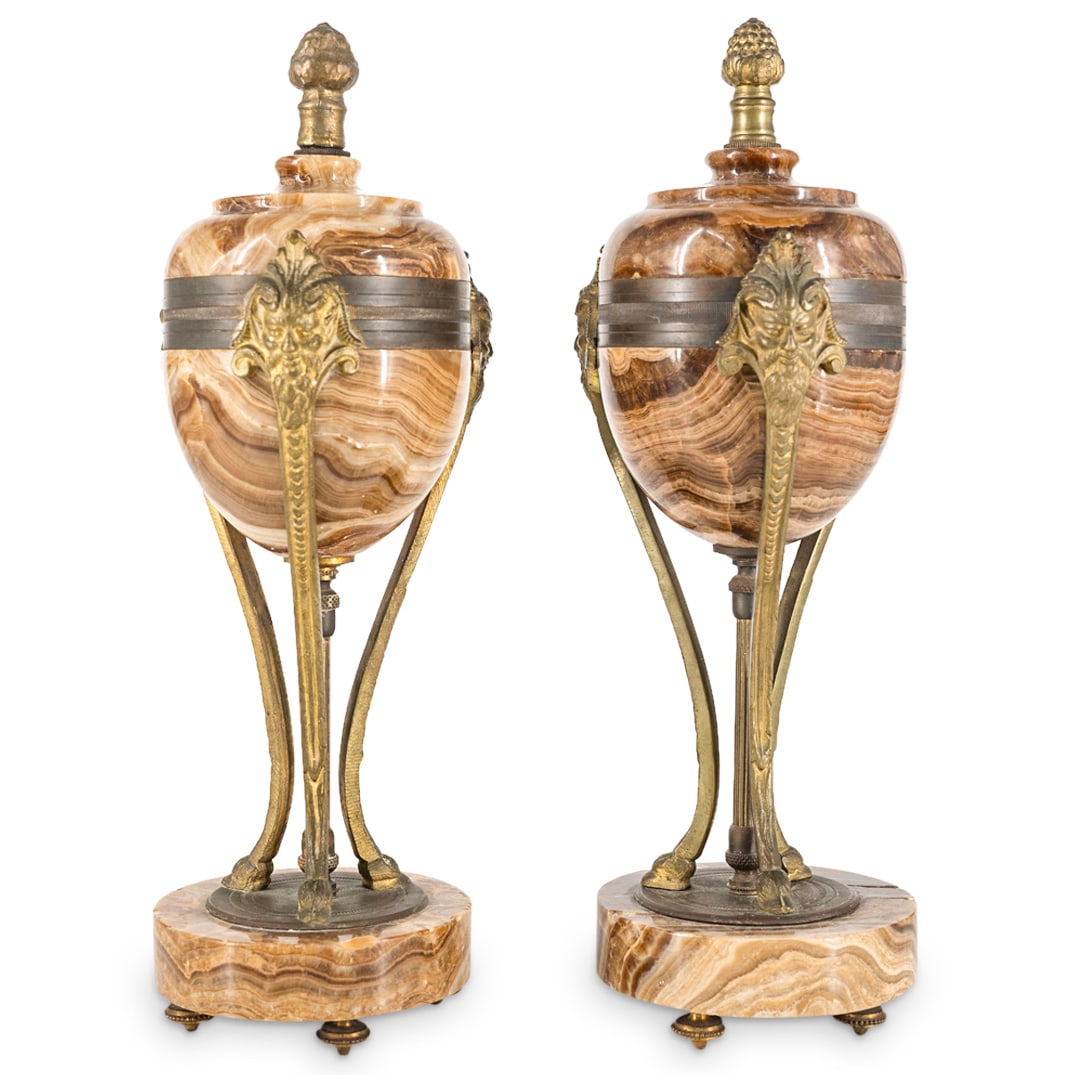 Pair Of Italian Granite, Gilt Bronze Satyr Urns: DESCRIPTION: Two matching sealed urns crafted from granite and gilt bronze trimmings, each featuring support for its body in the form of three satyr's heads atop legs with goat's hooves. Each piece is