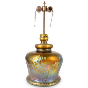 Antique French Iridescent Art Glass Table Lamp: DESCRIPTION: Antique double socket table lamp set into an art glass base featuring pulled iridescent accenting over a dimpled, gilt body. CIRCA: Late 19th to early 20th Century ORIGIN: France DIMENSIO