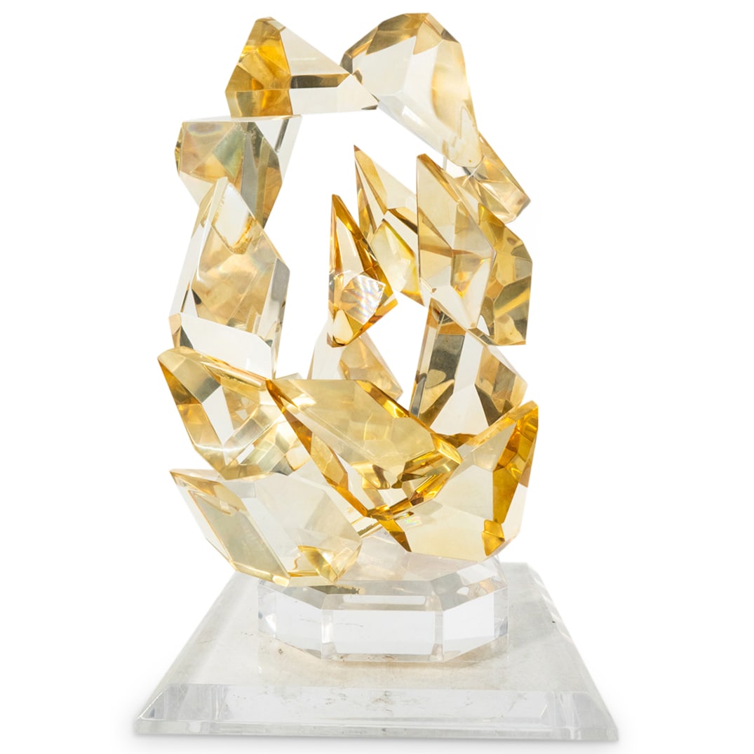 Signed R. Goddett "ENVY" Lucite Sculpture: DESCRIPTION: Lucite sculpture entitled "ENVY" depicting an abstract form composed of several gold-tinted and multi-faceted blocks connected into two rings and mounted on a clear lucite base atop a cle