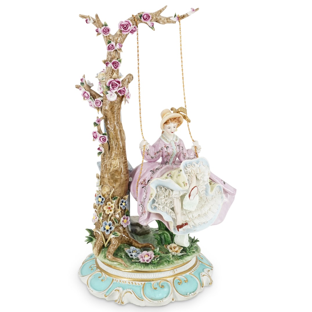 Dresden Woman On Swing Porcelain Group: DESCRIPTION: A Dresden porcelain group depicts a woman dressed in Edwardian garb swinging on a swing attached by gilt chains. Further decorated by floral applications throughout. Marked "underneath "D