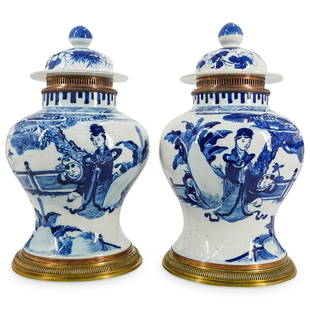 19th Cent. Chinese Blue and White Porcelain Bronze Mounted Urns: DESCRIPTION: A pair of 19th cent. blue and white porcelain urns, each decorated with deep blue figures in a courtyard setting. Adorned with a perforated bronze collar and ribbed base. Marked on unders