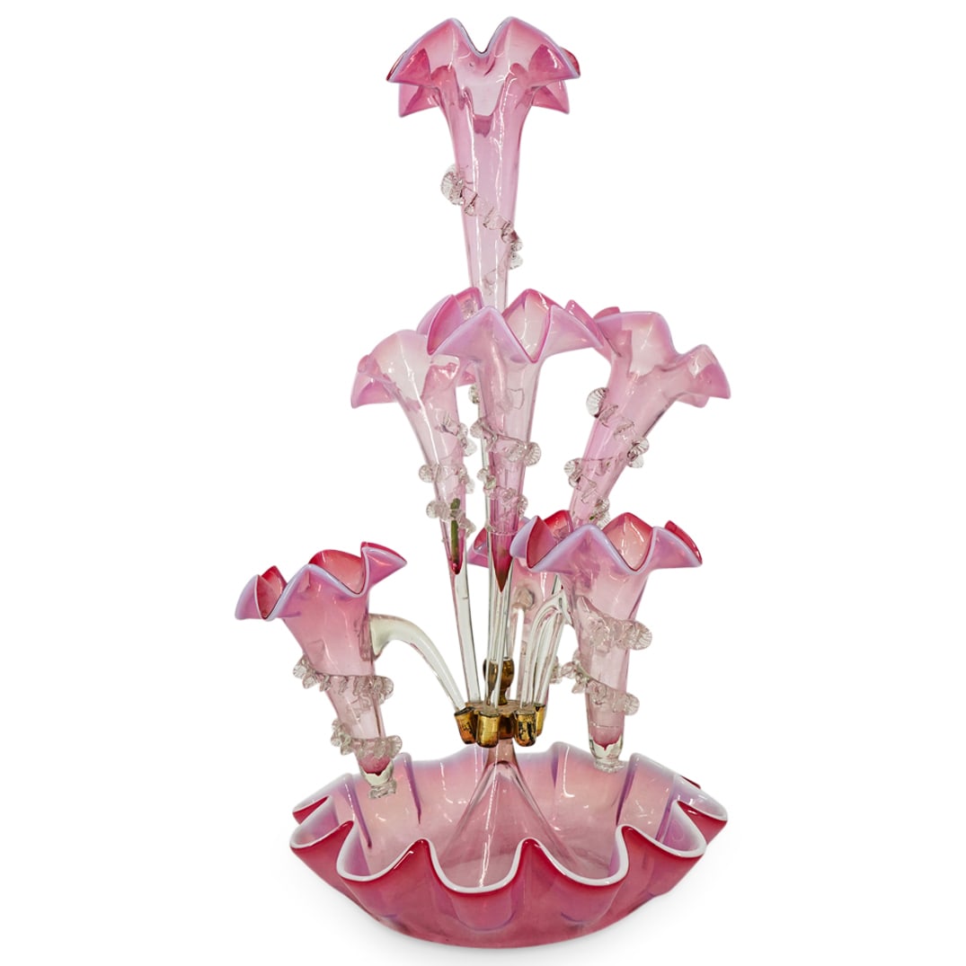 Antique Italian Pink Glass Epergnes: DESCRIPTION: Antique glass epergnes crafted from pink glass and featuring six cups surrounding a central cup all over a bowl base. Each cup has a kerchiefed lip and is ringed with a spiral finned appl