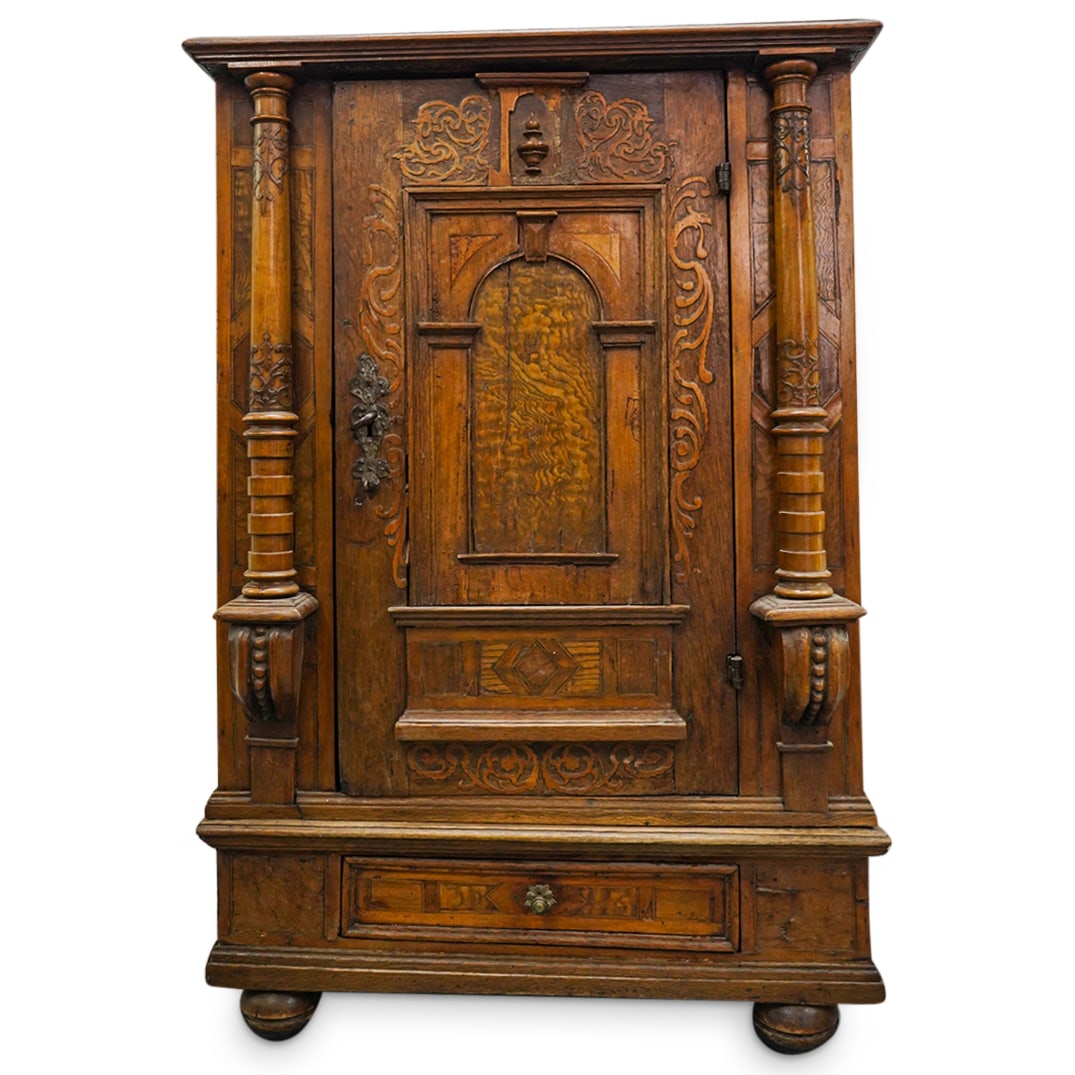 Antique South American Carved Wood Cabinet: DESCRIPTION: Carved wood cabinet crafted with a lower drawer beneath a door which opens to reveal a mirrored interior. Door is flanked by column reliefs and is fitted with a large, wrought-iron lock m
