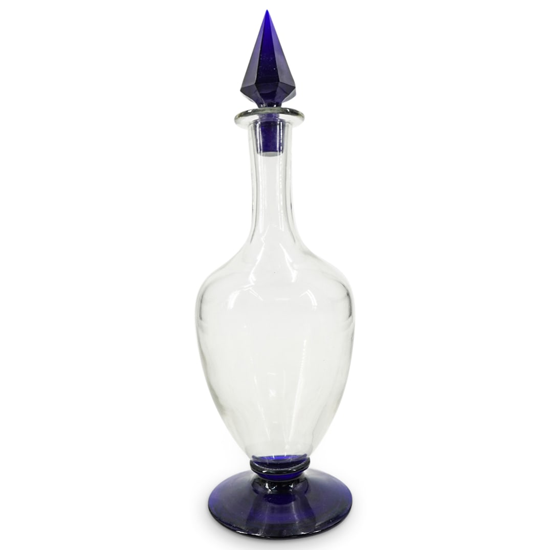 Vintage Murano Glass Clear And Blue Decanter: DESCRIPTION: Vintage Murano glass decanter featuring a clear glass body, a blue foot, and a blue stopper. Bears Bergdorf Goodman on underside. CIRCA: 20th Century ORIGIN: Italy DIMENSIONS: H: 13.25" D
