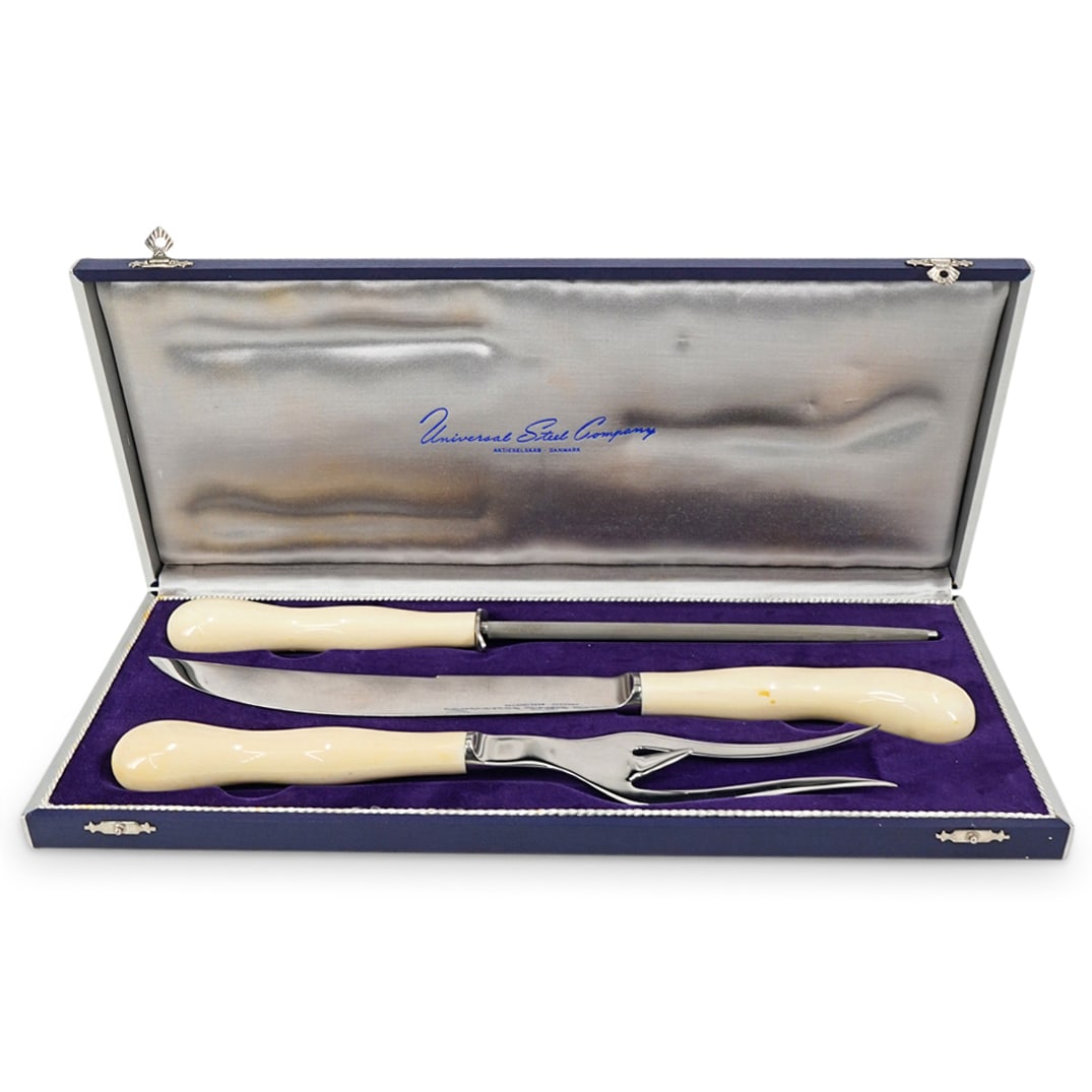 (3 Pc) Vintage Danish Universal Steel Company Meat Carving Set: DESCRIPTION: Carving set from the Universal Steel Company including one carving knife, one meat fork, and one honing steel, each with a carved bone handle. Pieces come in a silk-lined case. CIRCA: 20t