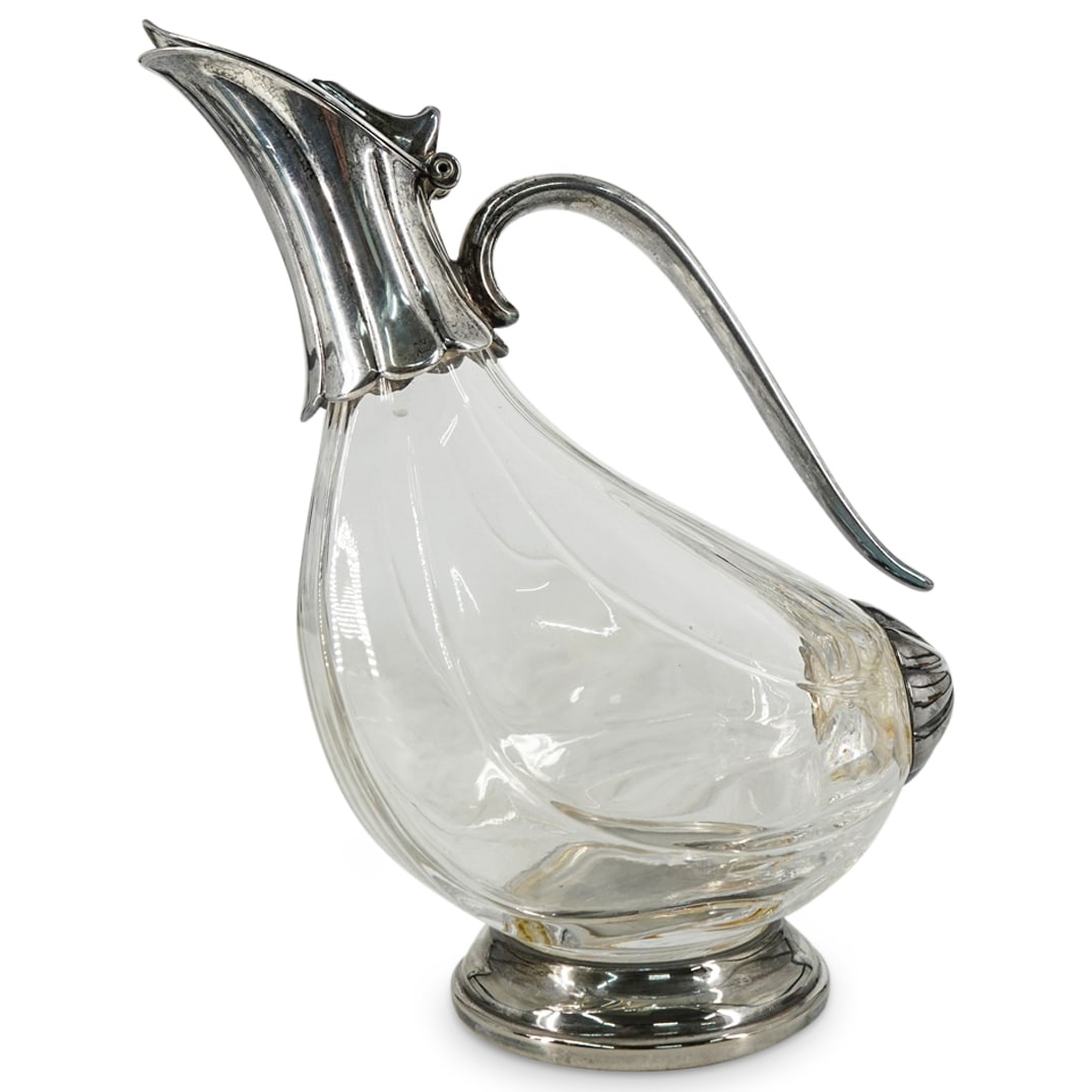Vintage European Silver Plated And Glass Ewer: DESCRIPTION: Vintage ewer composed of a ribbed glass body and a silver plated collar, lid, handle, and foot. Shape and silver plated cap on tail end results in an overall resemblance to a bird. CIRCA: