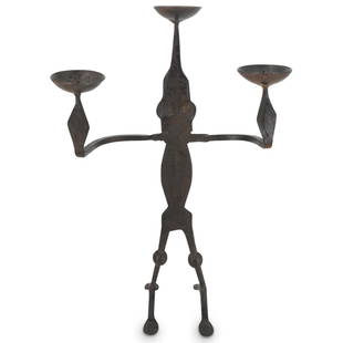 Cast Iron Figurative Candle Holder: DESCRIPTION: Cast iron three-arm candle holder, depicting a brutalist male figure with etched details such as eyes, nose and mouth. The head is designed to support one candle, and each arm is designed