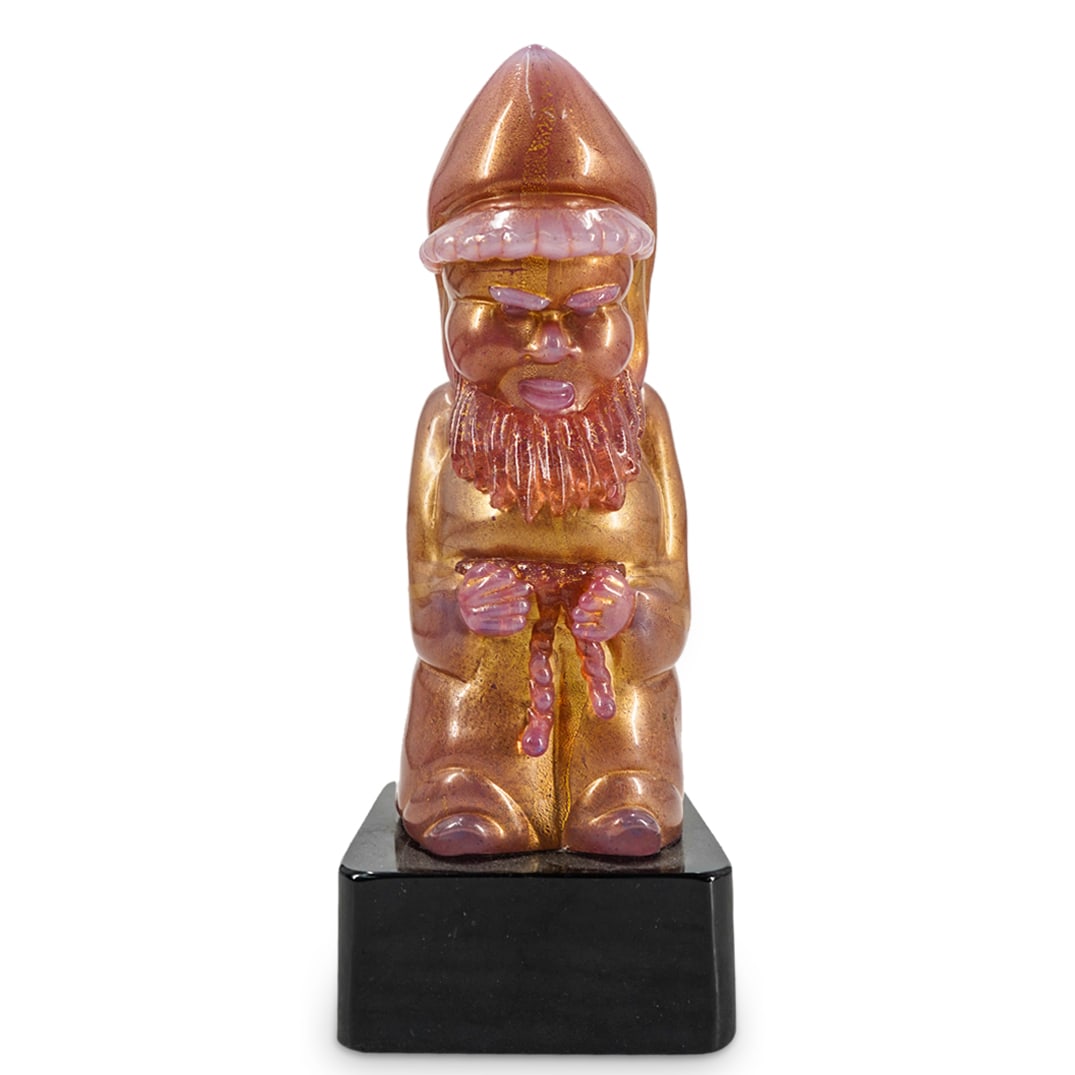 Murano Glass Gnome On Black Base: DESCRIPTION: Murano glass sculpture depicting a gnome In pink colored glass featuring gold foil flecks,. Mounted on black square glass base. CIRCA: 20th Century ORIGIN: Italy DIMENSIONS: H: 10.25" W: 
