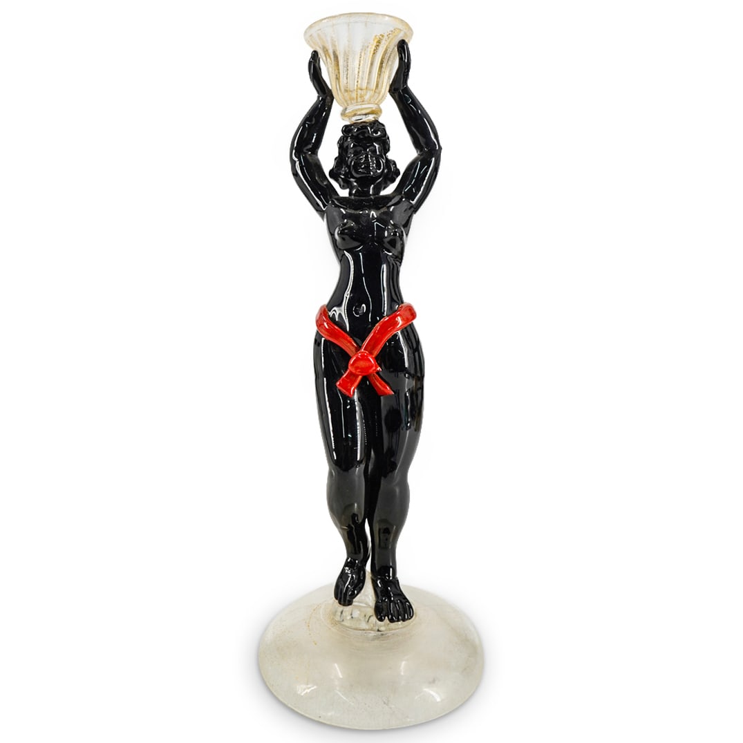 Murano Glass Figural Candlestick: DESCRIPTION: Murano glass figural candlestick fashioned in opaque black colored glass as a standing nude woman wearing a red colored sash and carrying a basket on her head while standing on a circular