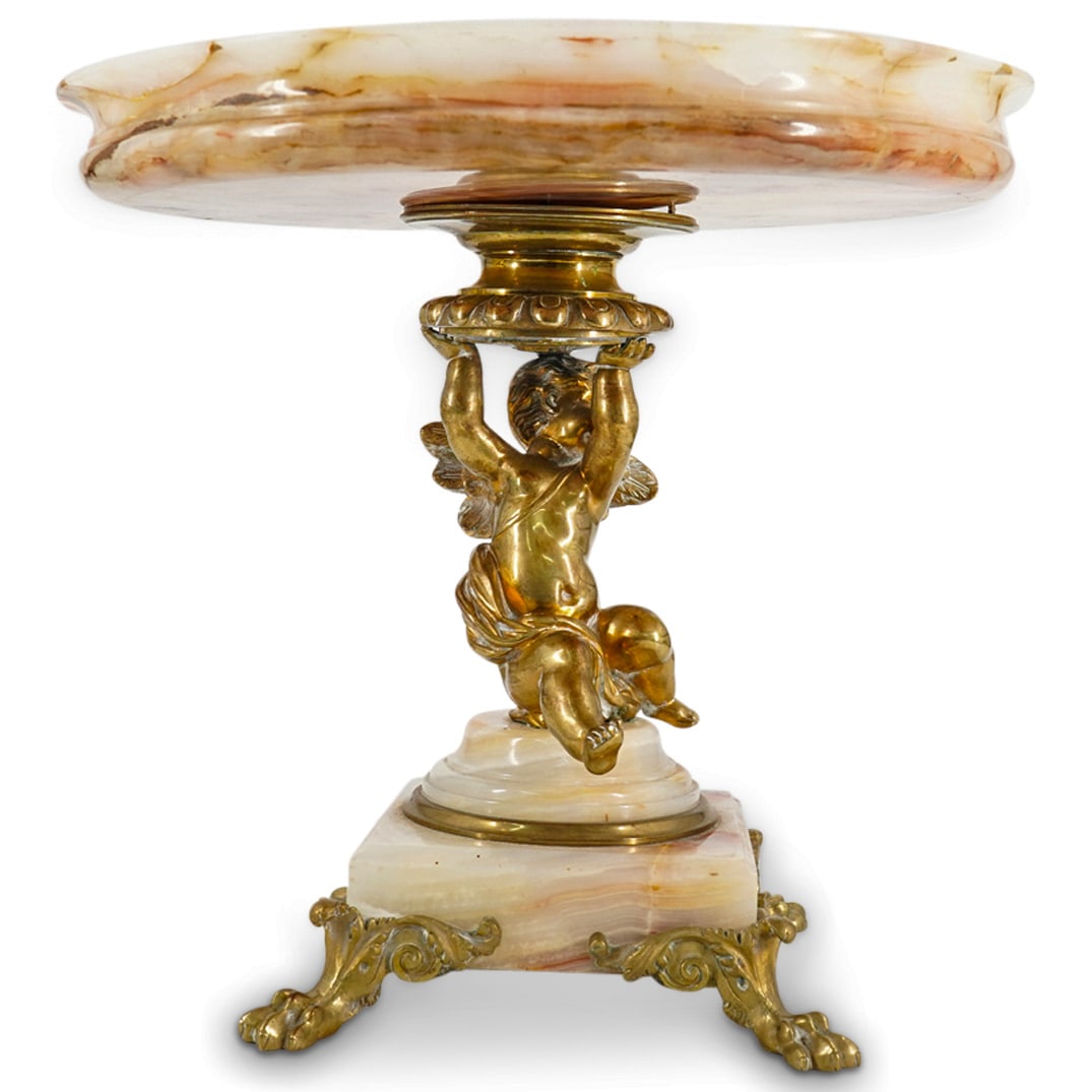 Neo Classical French Gold Gilt Bronze And Onyx Tazza.: DESCRIPTION: Neo classical French gold gilt bronze and onyx Tazza, the center of the bowl with a central medallion of 2 winged Putti, one Putto with a musical Lyle the other with pages of music as wel