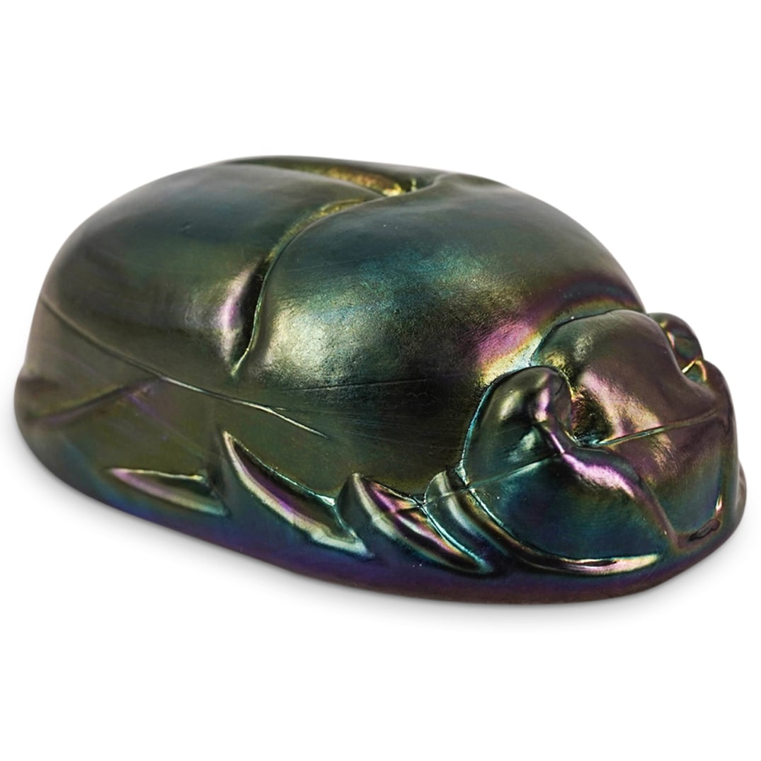 Iridescent Glass Scarab In The Manner Of Tiffany Studios.: DESCRIPTION: Iridescent glass scarab in the manner of Tiffany Studios. Inscribed indistinct signature on the bottom. CIRCA: 20th century ORIGIN: USA DIMENSIONS: H: 2" W: 2.5" L: 4.5" CONDITION: Excell