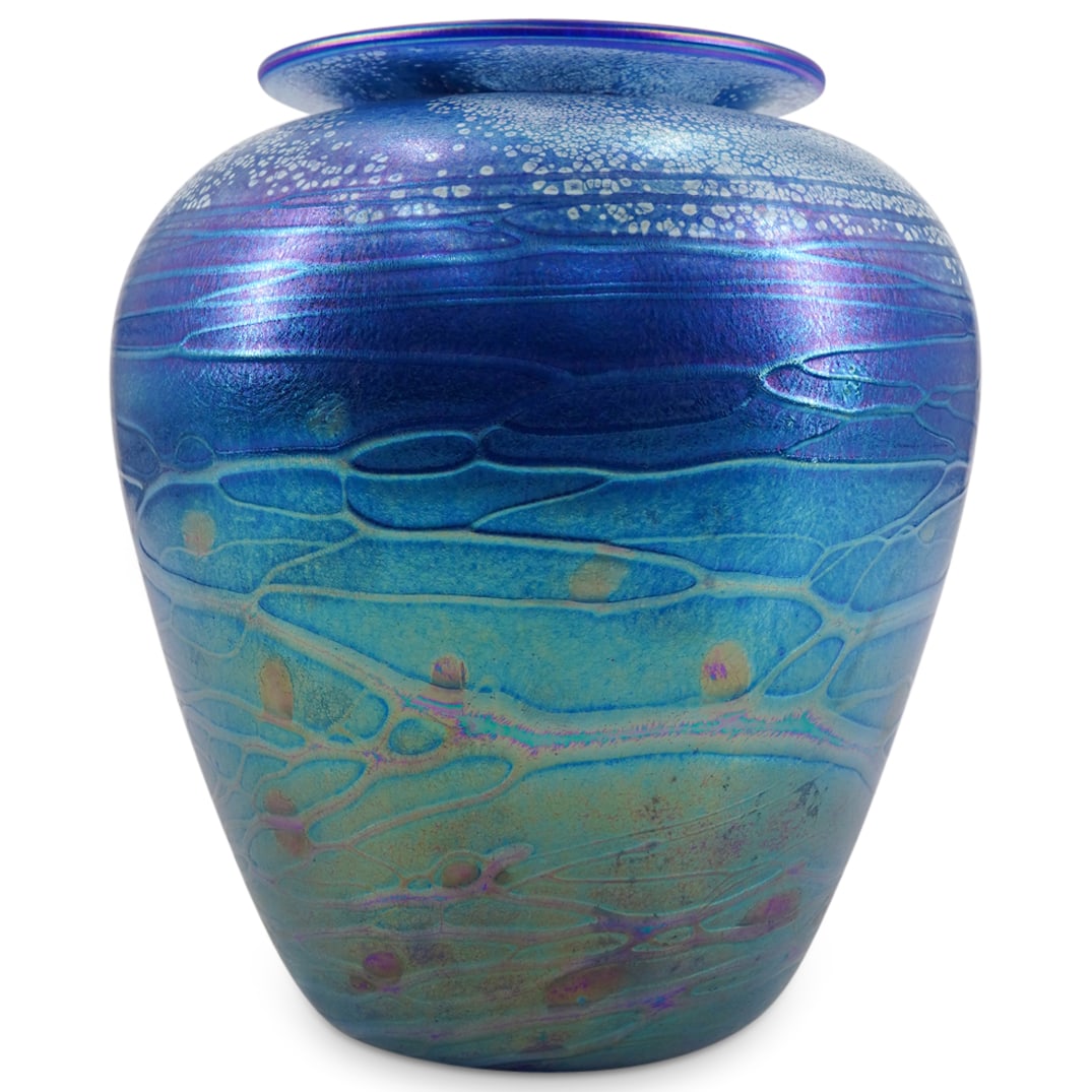Tom Stoenner Iridescent Art Glass Vase: DESCRIPTION: Iridescent studio art glass vase featuring a flared lip and sporting network of sporacid reeding around its body and light speckles around its shoulder. Signed on underside and dated "200
