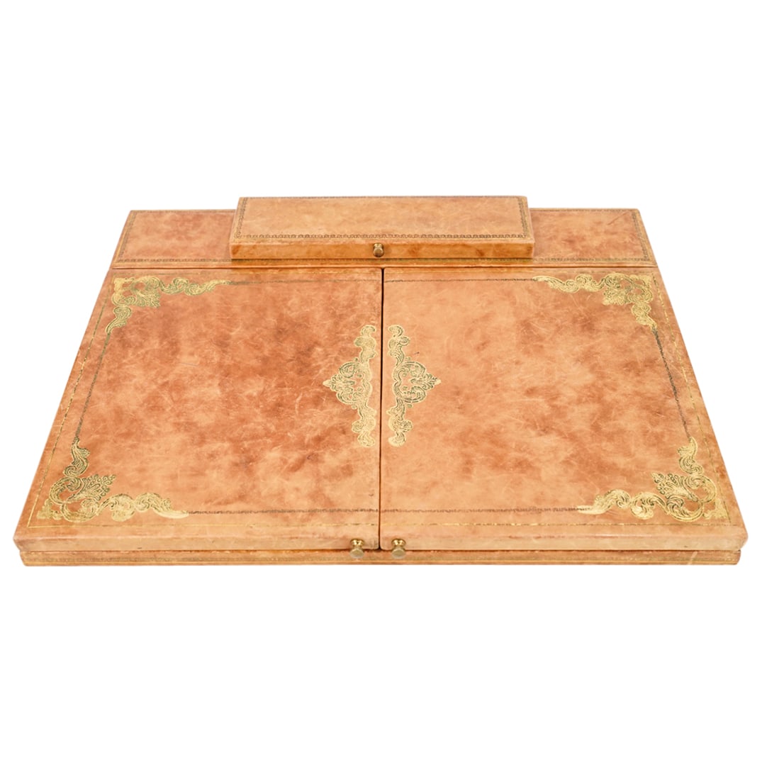 Mid Century Italian Leather Desk Blotter: DESCRIPTION: Mid Century Italian Leather Desk Blotter in walnut colored leather, with gold engraved decorative motifs. With a central aperture and hinged pencil compartment. CIRCA: Mid 20th Century OR