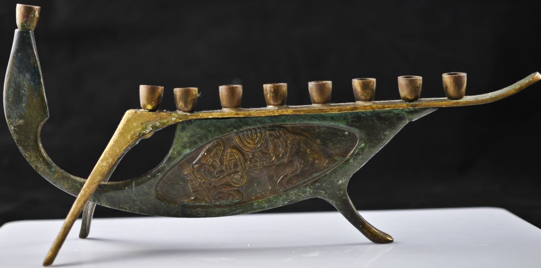 Judaic bronze three footed menorah with carved scen: DESCRIPTION: Unusually designed Judaic bronze menorah featuring three feet and double sided Judaic scenes. Well aged patina. Engraved on bottom "Made in Israel" CIRCA: 1940s MADE IN: Europe DIMENSIONS