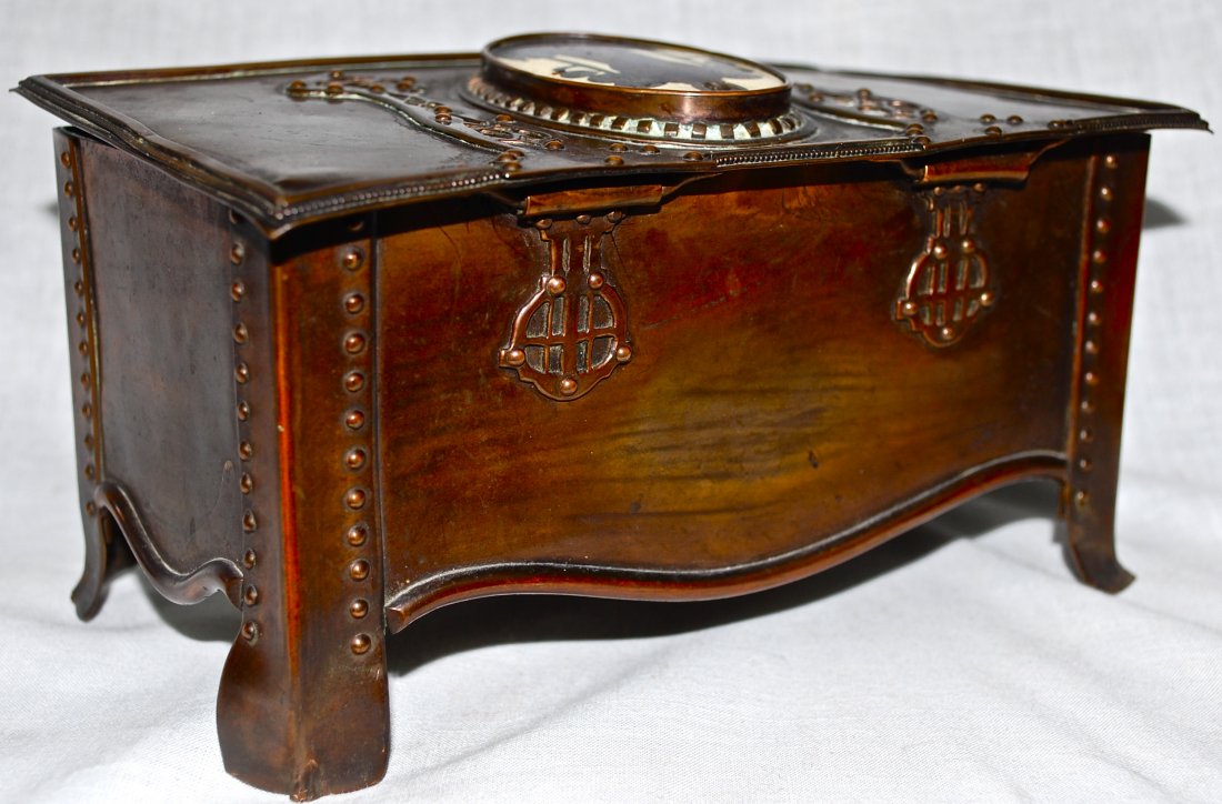 Copper, cloisonné and mother of pearl jewelry box: DESCRIPTION: Unusual antique copper jewelry box. Top lid is enameled cloisonné depicting a scene of a lone person standing in front of two symmetrical trees. The elongated hinges cover two plates of 