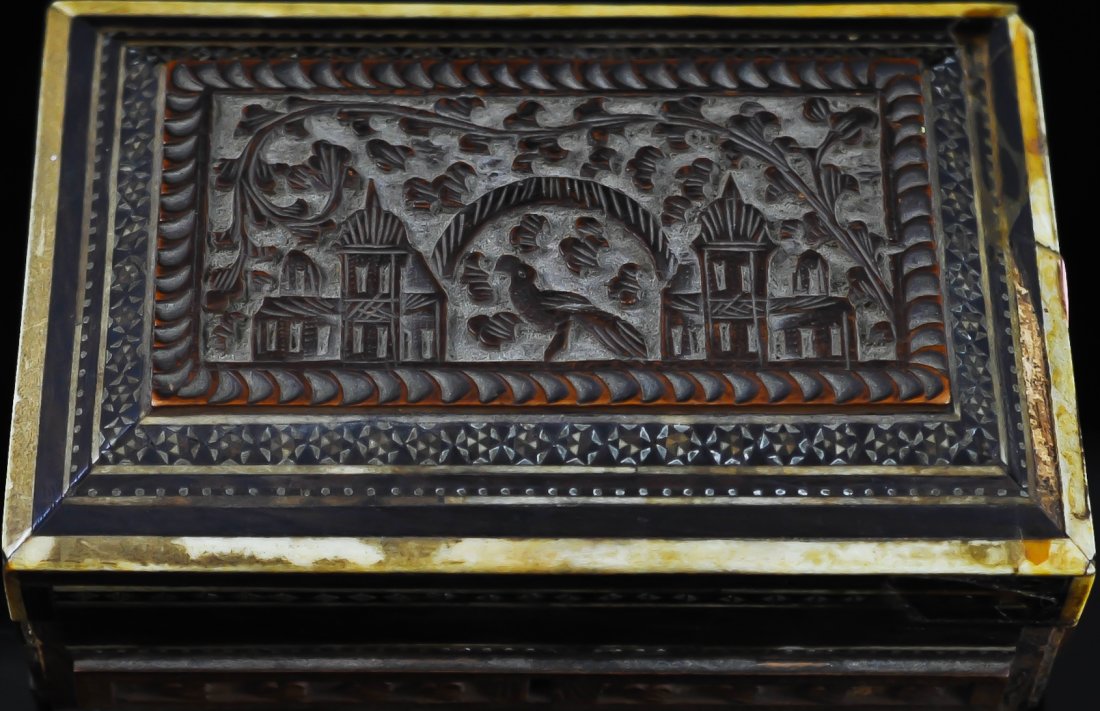 Antique hand carved wooden box w/ mother of pearl: DESCRIPTION: Hand carved wooden box with mother of pearl and ivory inlaid tiles. The lid features a carved village scene with a bird as the center piece. Missing a couple of pieces. Brass hardware. CI