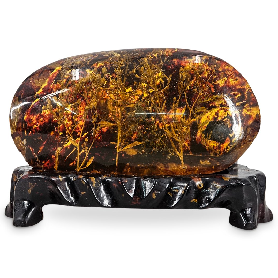 Copal/Amber Gemstone With Floral Inclusions: DESCRIPTION: Copal/amber gemstone with floral inclusions with copal/amber with a fitted copal/amber stand. Weight 2,150 grams. CIRCA: Mesozoic era ORIGIN: Colombia DIMENSIONS: H: 5" L" 8.5" D; 3.5" CO