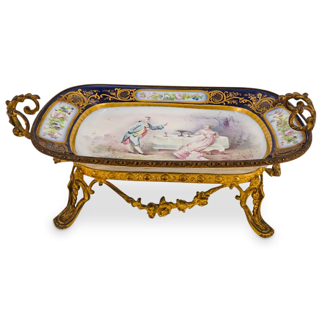 French Sevres Porcelain Painted Tray: DESCRIPTION: French Sevres porcelain painted tray with gold gilt bronze foliate (4) legged stand and scrolled handles. Marked with the Sevres mark, as well as painted ""France" on the back. CIRCA: Ear