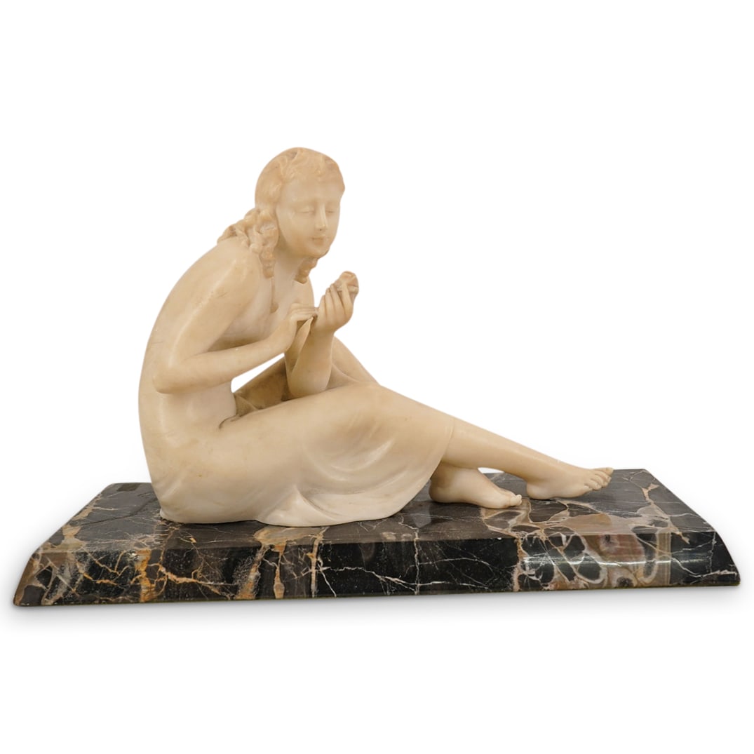 Alabaster Carved Figurine of a Victorian Lady: DESCRIPTION: Alabaster carved figurine of a Victorian lady holding and looking at a rose. Mounted on a beveled black veined marble base. CIRCA: 1910 ORIGIN: France DIMENSIONS: H: 8" W: 12" D: 5" CONDI