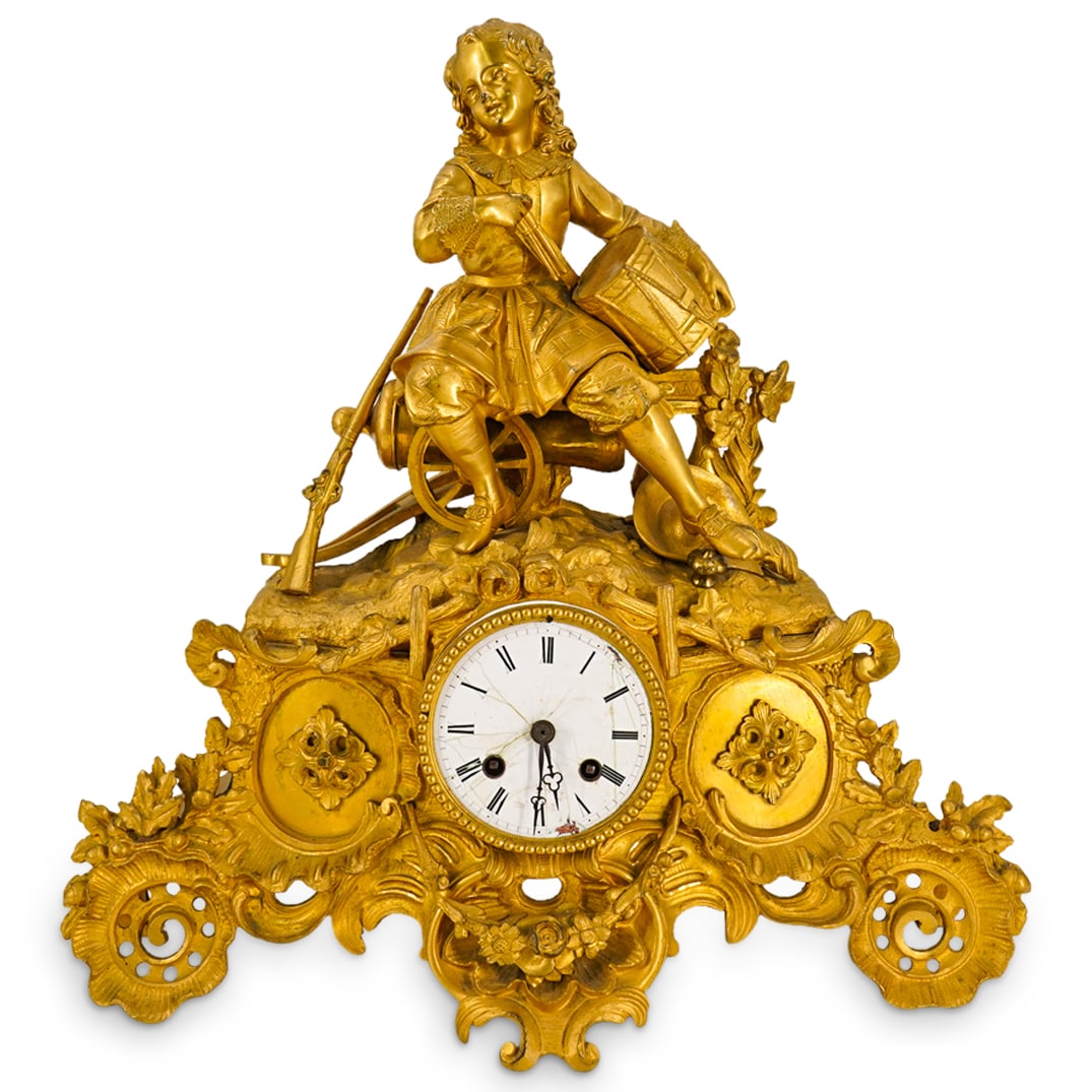 Antique French Japy Freres Figural Mantel Clock: DESCRIPTION: Antique Japy Freres et Cie mantel clock composed of a movement mounted in a gilt brass housing featuring a boy holding a drum while seated on a cannon next to a rifle and a hat. Movement