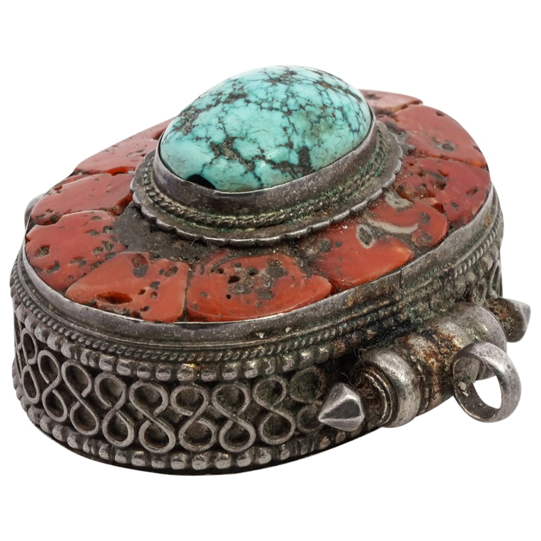 Antique Tibetan Coral, Turquoise & Silver Gau Pendant: DESCRIPTION: Antique Tibetan silver gau pendant decorated with circular border and inset turquoise and coral. CIRCA: 19th century ORIGIN: Tibetan DIMENSIONS: H: 1.75" W: 1.5" Depth: 0.75" CONDITION: A