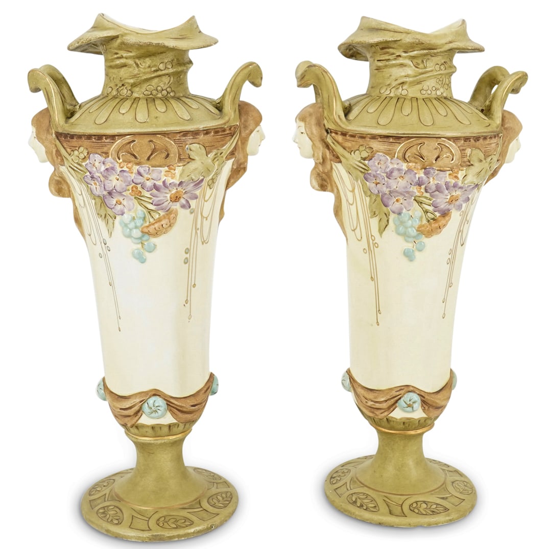 (2 Pc) Art Nouveau Porcelain Vases: DESCRIPTION: Pair of Art Nouveau porcelain vases, each decorated with floral designs beneath the shoulders, a woman's face between each of the two handles, and gilt accents. CIRCA: 20th Century ORIGIN