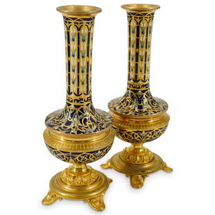 Pair Of Attr. To Barbedienne Champleve Bud Vases: DESCRIPTION: Two matching champleve bud vases attributed to Ferdinand Barbedienne, each featuring enameled flowers and foliage in shades of blue and sporting gilt outlines and gilt, four-footed bases.