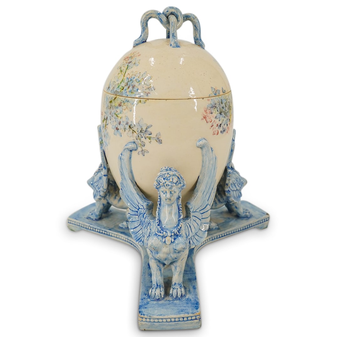 Antique French Majolica Pottery Sphinx Egg Centerpiece Vase: DESCRIPTION: Antique French majolica pottery covered centerpiece vase with egg form supported by three winged Sphinx in a delicate blue glossy glaze, egg finished with an open-work intertwined handled