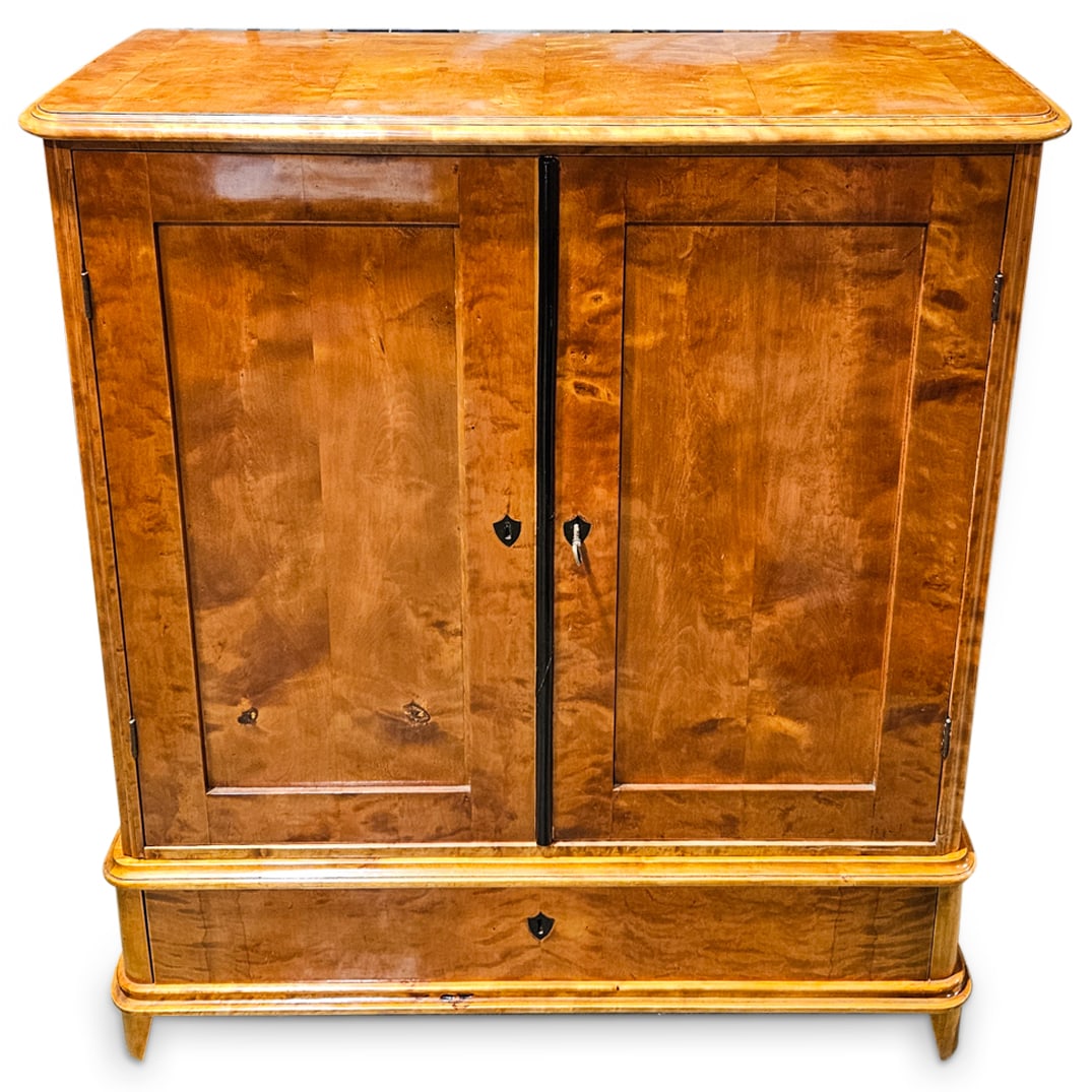 Biedermeier Secretaire Cabinet: DESCRIPTION: Biedermeier secretaire cabinet composed of satin wood with double center doors and lower pull-out storage drawer, designed with inset shield formed keyholes and ebonized accents. CIRCA: L