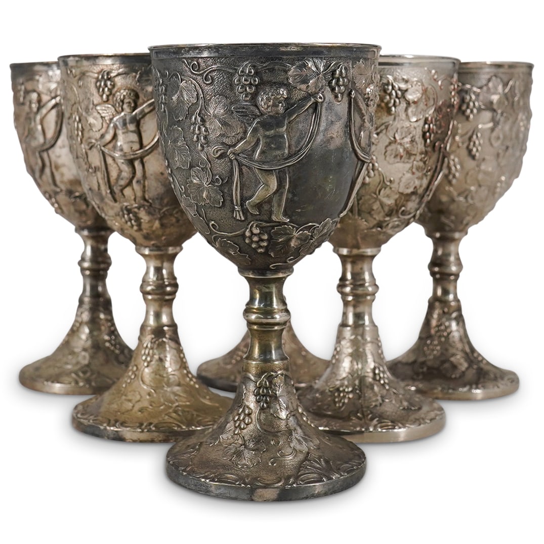(6 Pc) Set of Silver Plated Wine Goblets: DESCRIPTION: A set of six silver plated wine goblets decorated along the body with raised grape vine clusters wit greco roman putti figures. Marked along the underside with indistinct makers mark. CIR