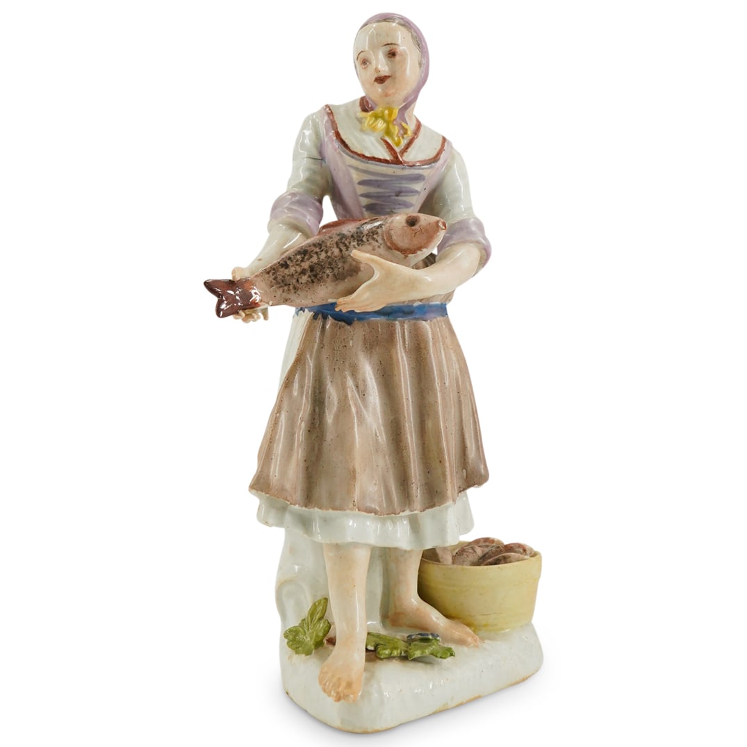 18th Cent. Meissen Porcelain Figure of A Fish Seller: DESCRIPTION: an 18th cent. porcelain Meissen figure depicts a woman fish seller designed by Johann Joachim Kaendler. The seller is seen holding a large fish with a basket placed along her feet, comple